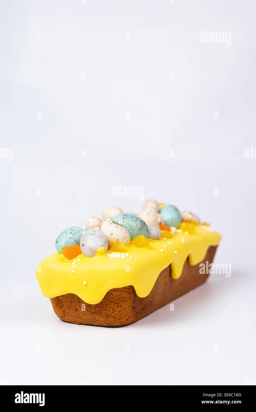 Osterbrotkuchen mit gelber Zuckerglasur und Süßeiern isoliert Stockfoto