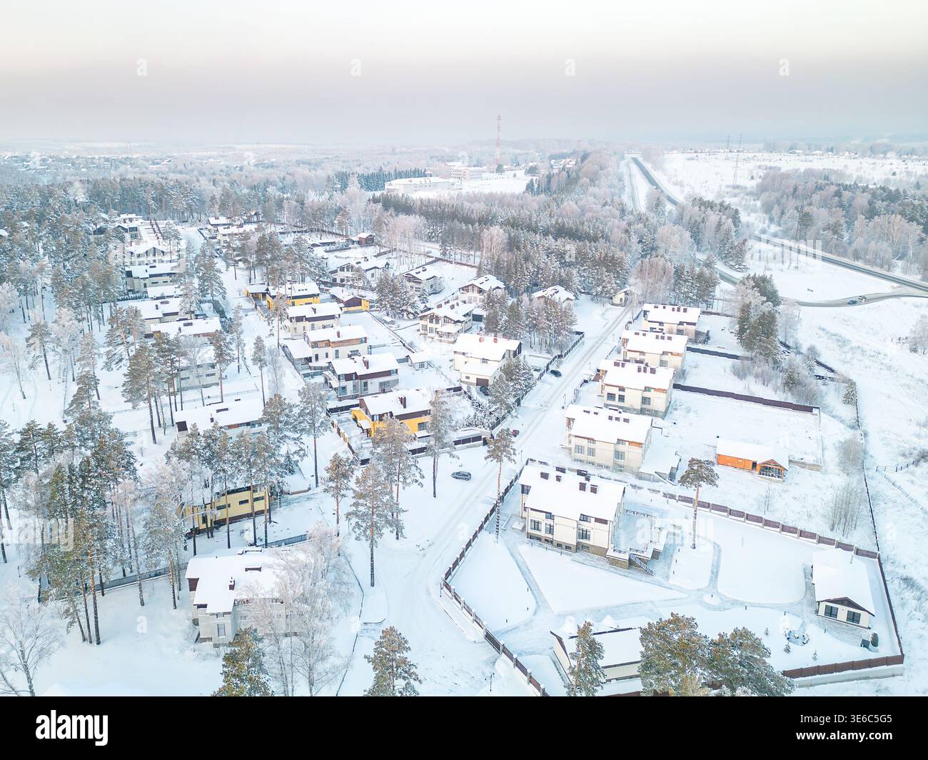 Drohnenfoto von moderner Wohnsiedlung mit umzäunten Grundstücken und winterlicher Waldlandschaft am Stadtrand, selektiver Fokus Stockfoto