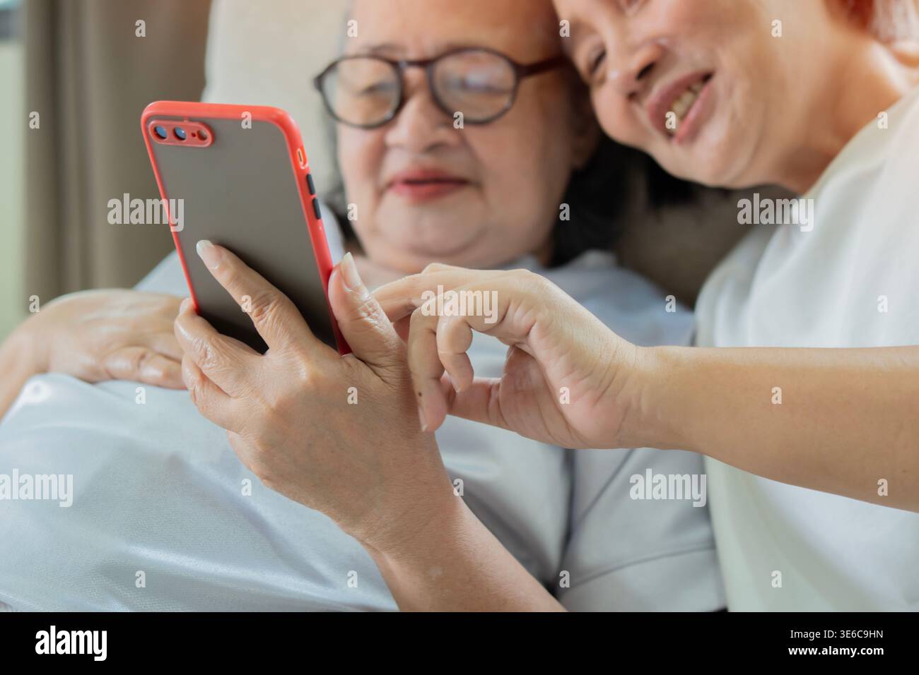 Multirassische Seniorinnen und junge Frau, die zu Hause Videoanrufe per Smartphone hat. Ältere Menschen und Technik. Selektiver Fokus. Stockfoto