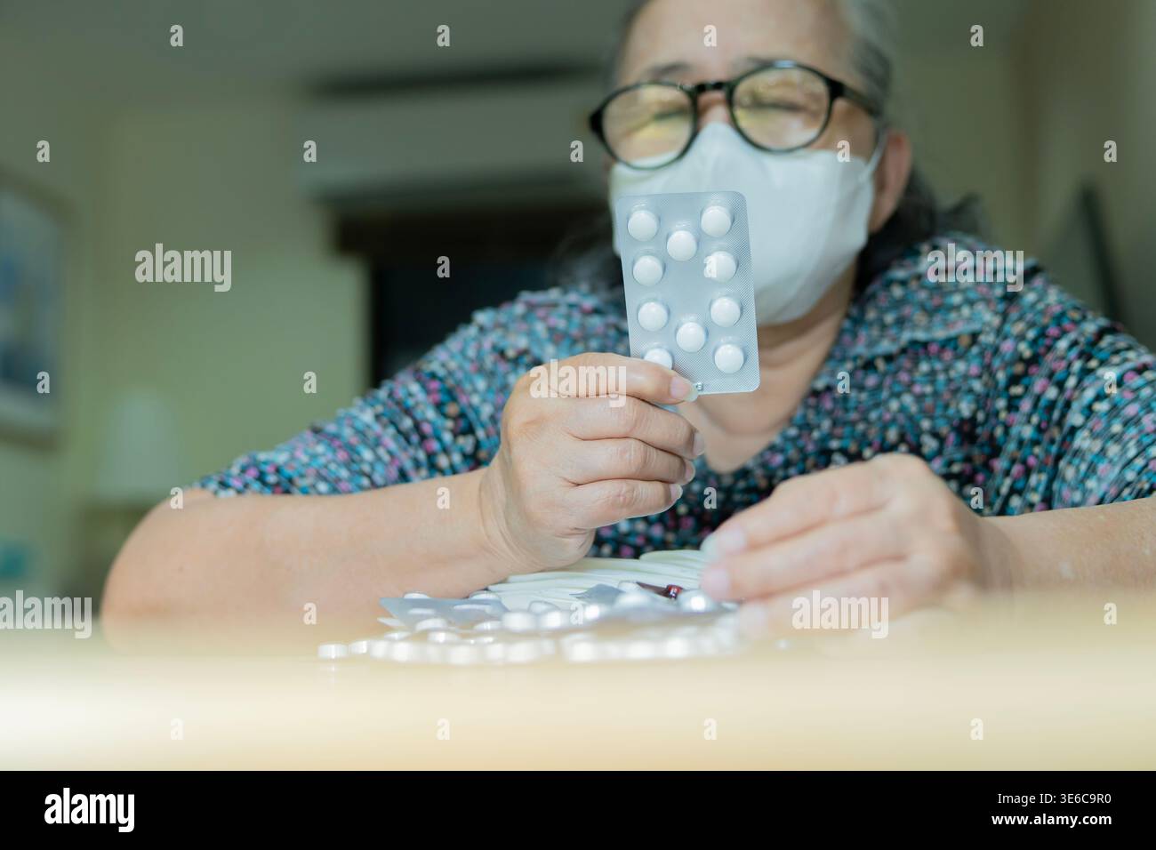 Schuss der älteren asiatischen Frau, die verschreibungspflichtige Medizin Pack und Blisterpackung der Pillen auf Holztisch hält, die Healthcare Apotheke und Senior wir repräsentieren Stockfoto