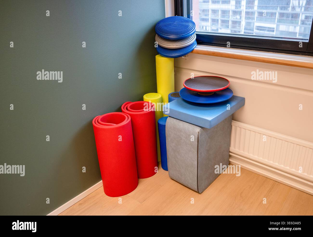 Farbenfrohes Fitnessgerät-Set mit Yogamatte, Schaumgummi und Trainingsgeräten in modernem Fitnessraum Stockfoto