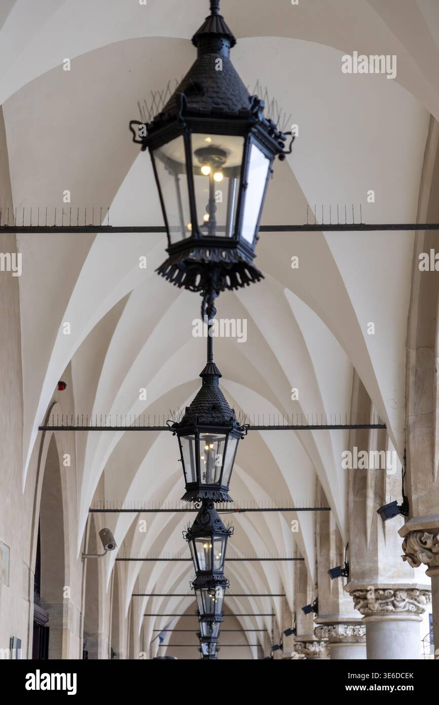 Die detaillierte, flache Ansicht zeigt elegante Vintage-Windlichter aus schwarzem Metall, die symmetrisch in einer historischen europäischen Arkade hängen und einen zeitlosen Bogen zeigen Stockfoto