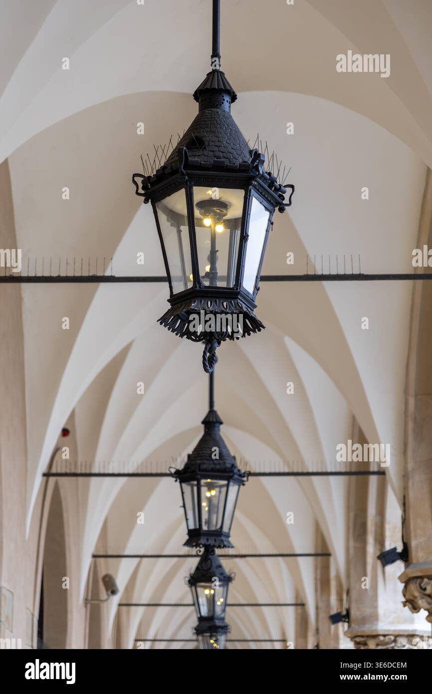 Ein detaillierter Blick auf mehrere verzierte Vintage-schwarze Laternen, die in einer langen, gewölbten Passage hängen und das elegante Design und das historische Ambiente hervorheben Stockfoto