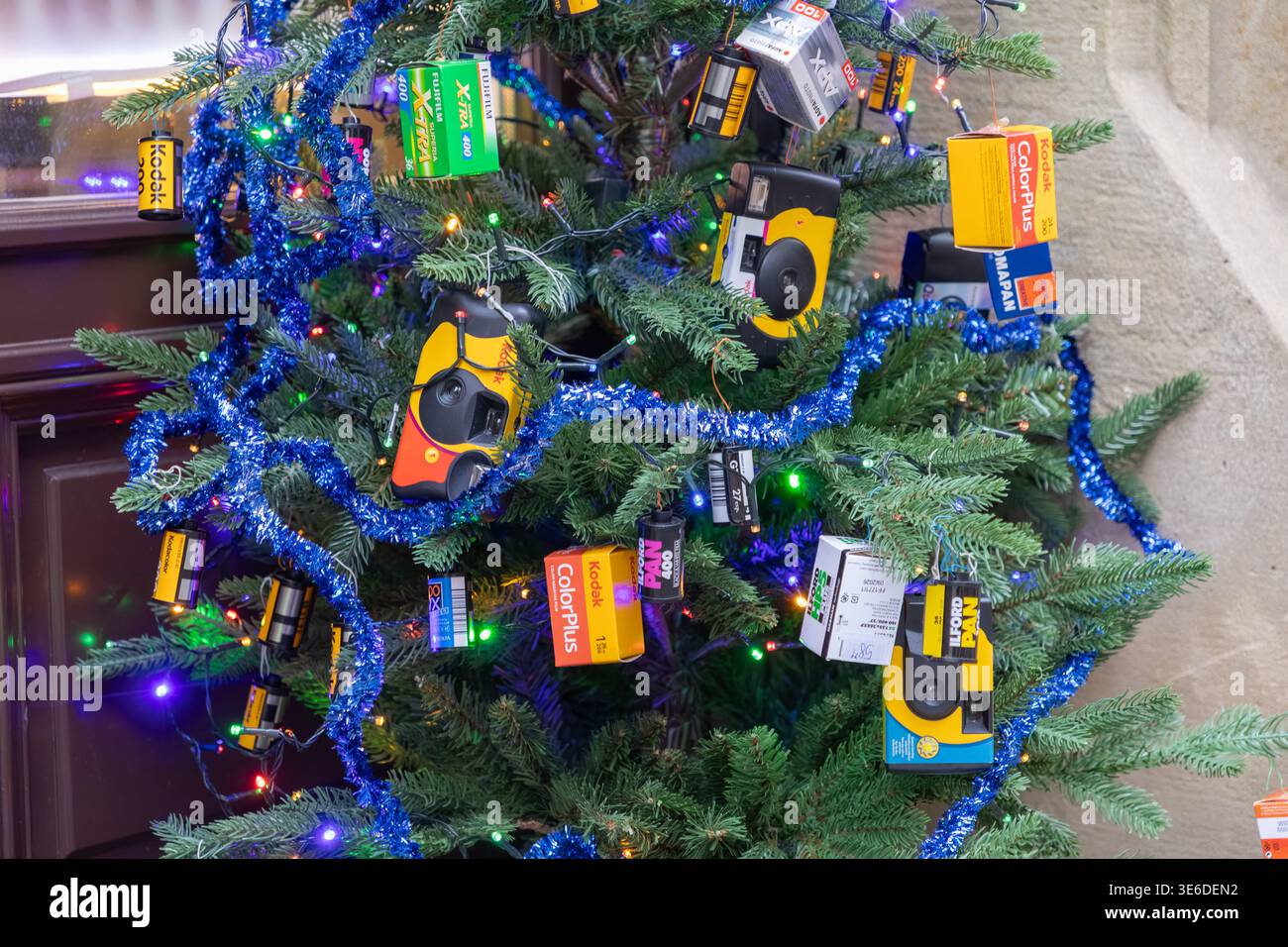 Krakau, Polen - 1. Dezember 2025: Festliche Festvorstellung mit einem lebendigen Weihnachtsbaum mit blauem Lametta, Lichtern und dem Vintage Kodak, Fujifilm f Stockfoto