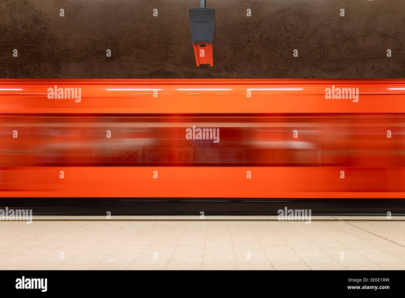 Unscharfe Bewegung eines orangen U-Bahn-Zuges an der Metrostation Kamppi in Helsinki, Finnland Stockfoto
