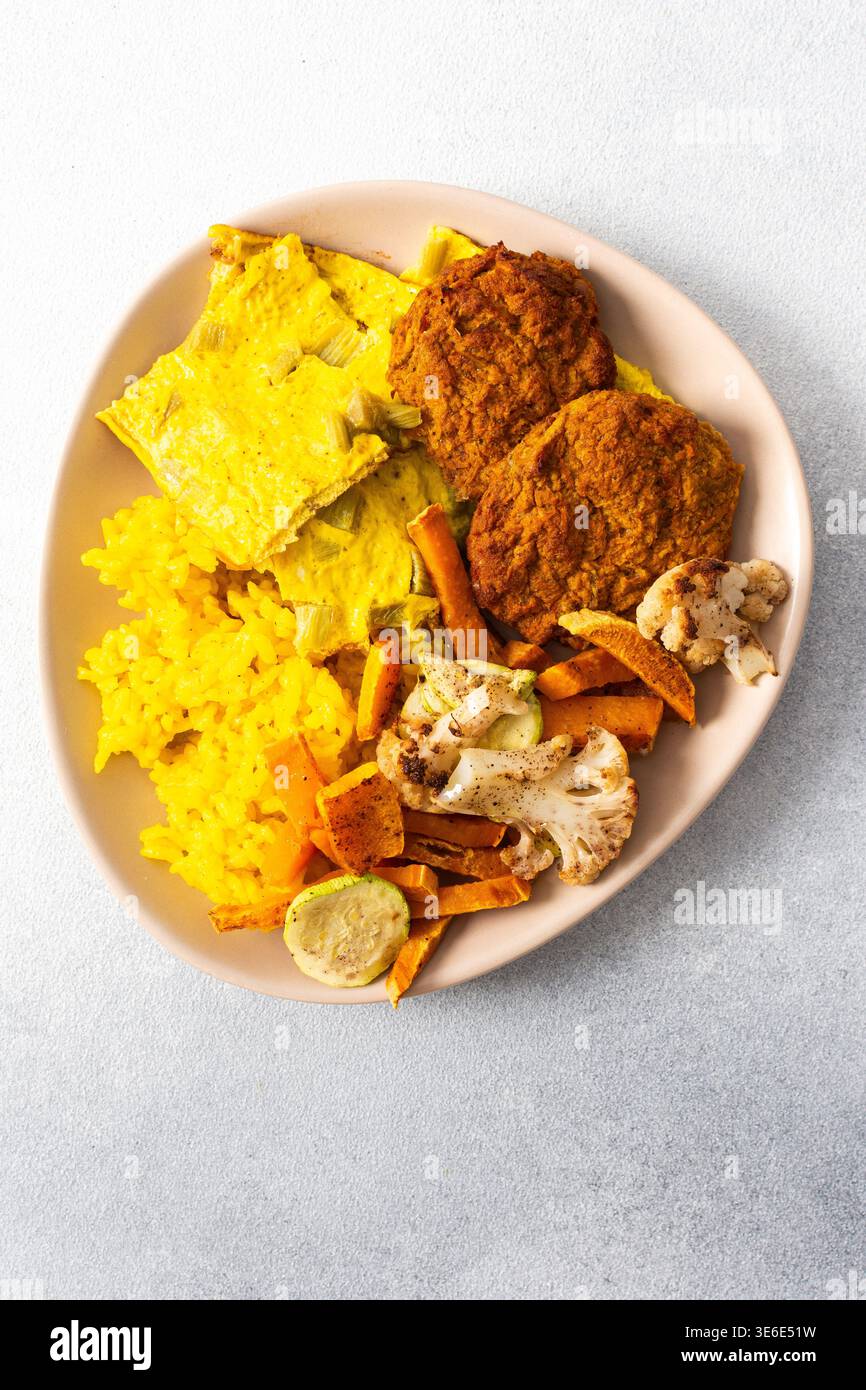 Ein lebhafter Teller mit flauschigem gelbem Reis, cremigen Rhabarber-Spiegeleiern und knusprigen Fleischgerichten bietet eine herzhafte und geschmackvolle Mahlzeit, die perfekt für einen ist Stockfoto