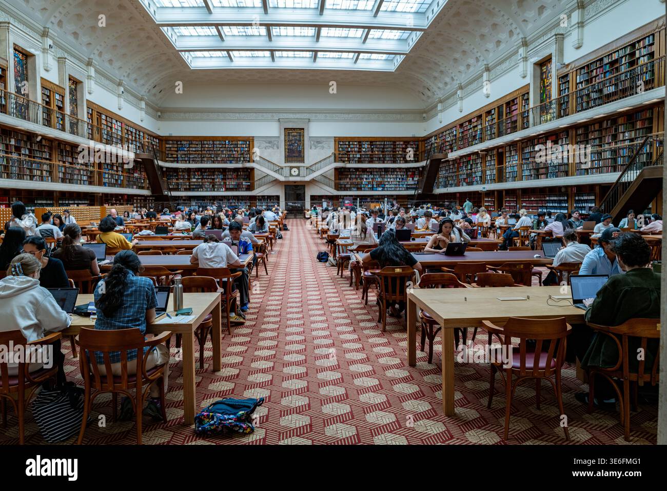 Innenraum des historischen Mitchell Reading Room in der State Library of New South Wales, in dem Besucher an langen Holztischen studieren. Stockfoto