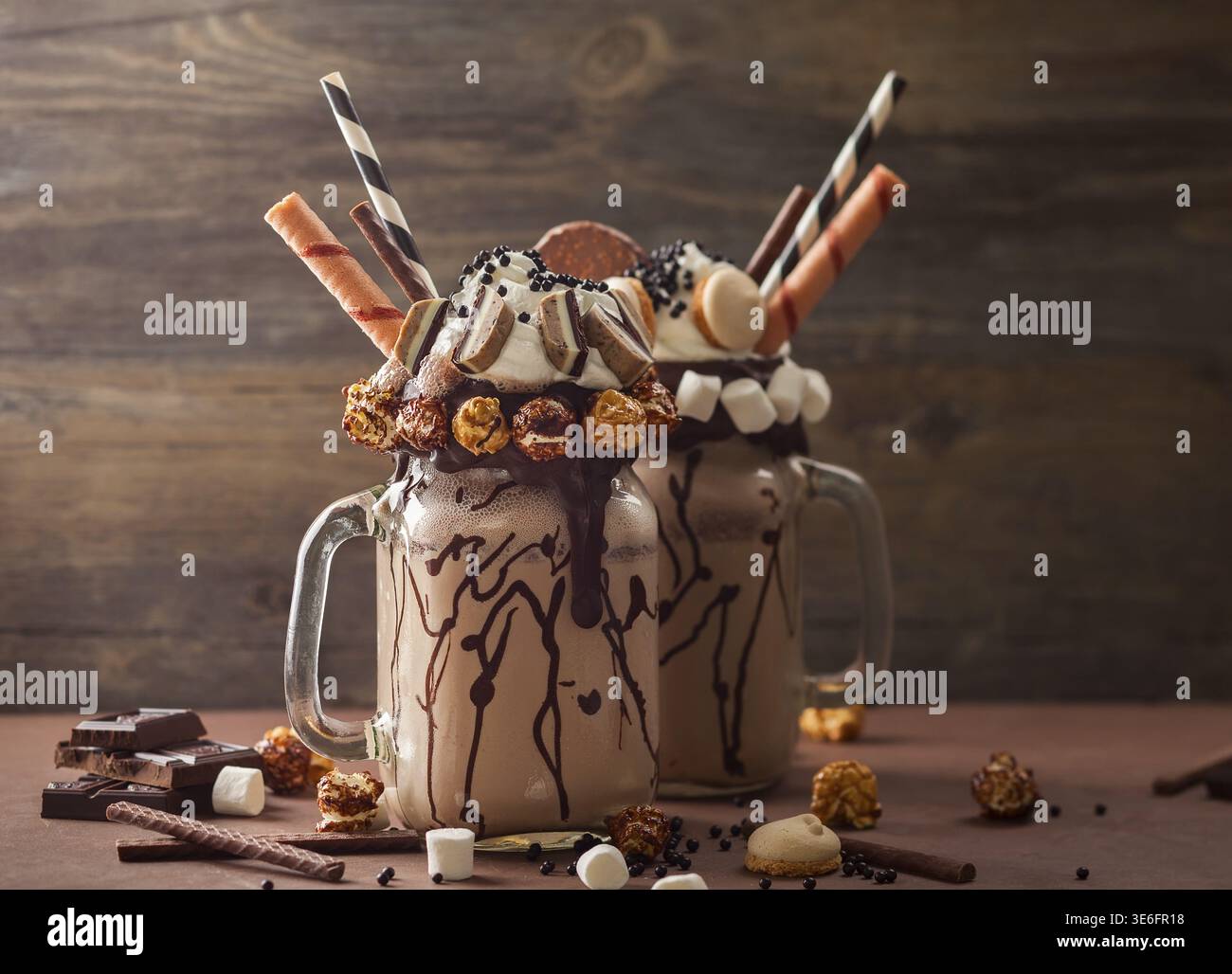 Schokoladenmilchshake mit Eis und Schlagsahne, Marshmallow, süßem Popcorn, Keksen, Waffeln, serviert in glasmauerglas Stockfoto