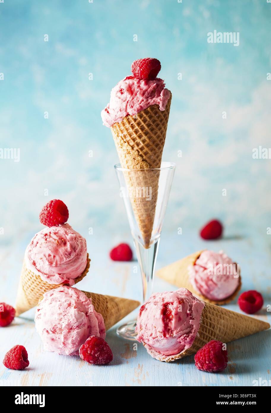 Eis mit Himbeere im Waffelkegel auf blauem Hintergrund Stockfoto