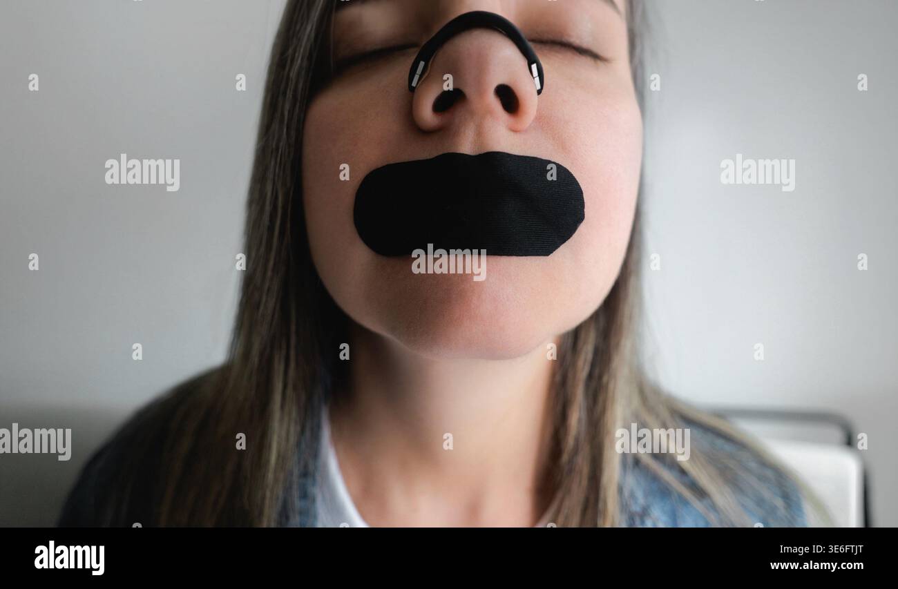 Frau mit Nasenstreifen und Mundband für besseren Schlaf und Atmung - Biohacking und Wellness-Konzept Stockfoto