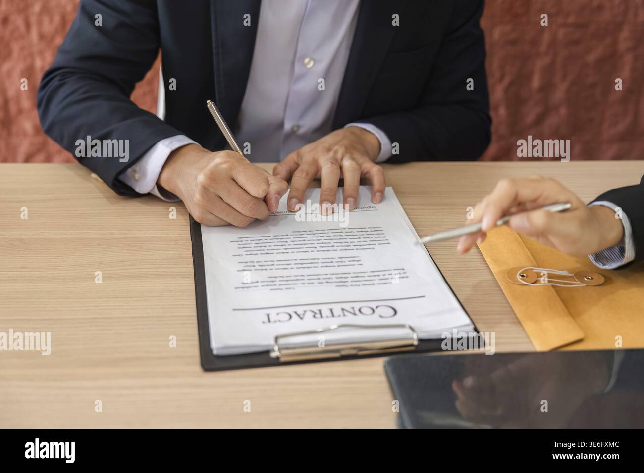 Zwei Fachleute haben einen formellen Vertrag unterzeichnet, um Zusammenarbeit und Vertrauen in ihre Geschäftsbeziehungen zu demonstrieren Stockfoto