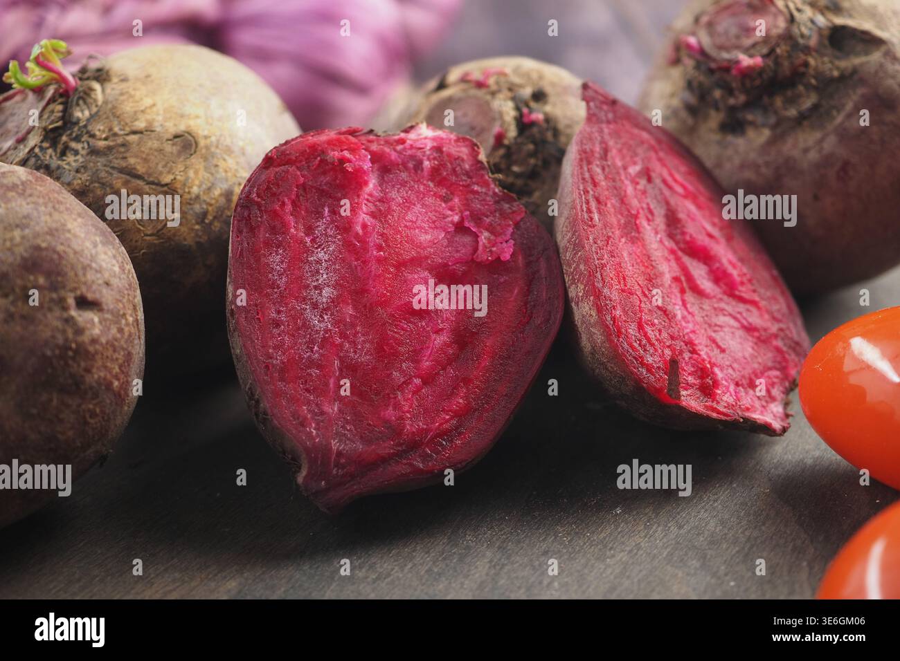 Rüben halbieren neben ganzen Rüben auf Holztisch Stockfoto