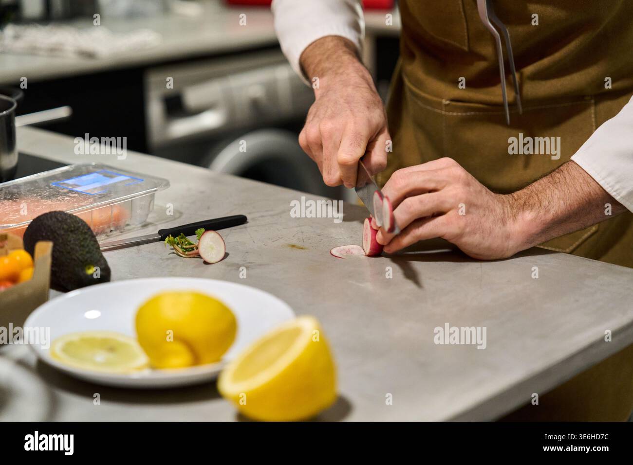 Küchenchefs bereiten frische Rettichscheiben auf einer Küchentheke zu, wobei der Schwerpunkt auf gesundes Kochen und Zubereitung von Mahlzeiten liegt Stockfoto