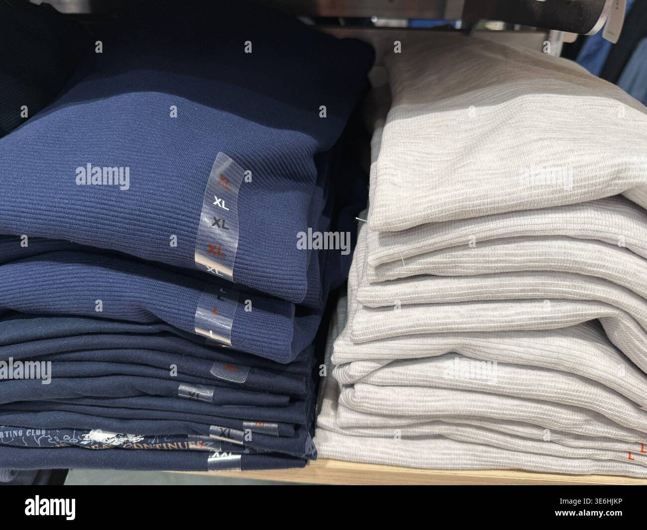 Gefaltete Kleidung im Ladenregal mit verschiedenen Farben und Größen für die Präsentation im Fashion-Einzelhandel. Mobiles Foto Stockfoto