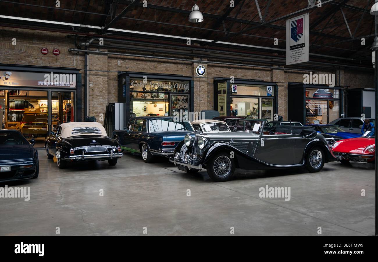 Oldtimer und europäische Klassiker parken in der Classic Remise Garage. Seltene alte Autos, die in der historischen Industriearchitektur in Berlin ausgestellt werden. Stockfoto