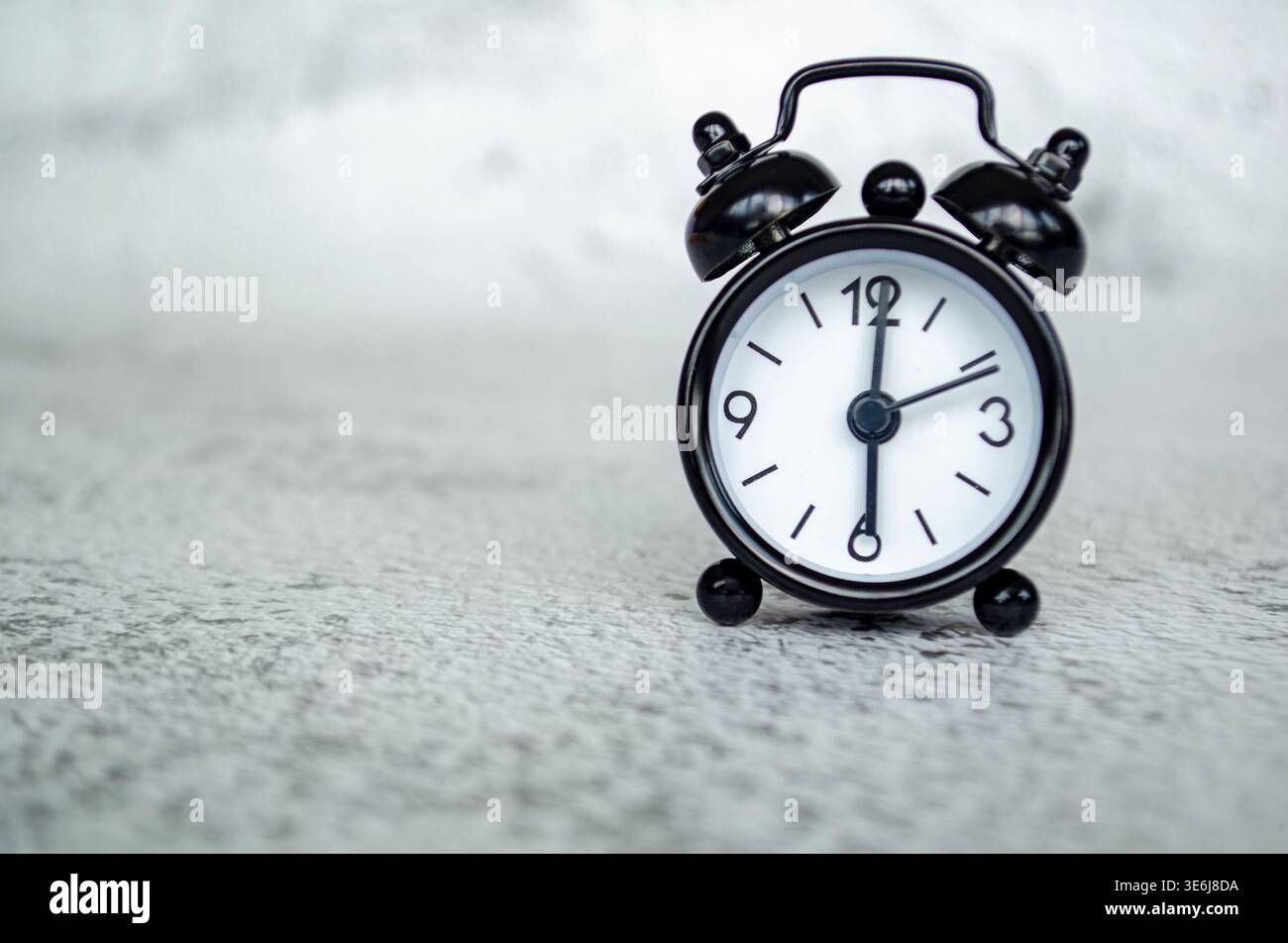 Minimales Miniaturbild für den Wecker in Schwarzweiß, das ein frühmorgendliches 6-Uhr-Konzept auf einem strukturierten grauen Hintergrund zeigt. Stockfoto