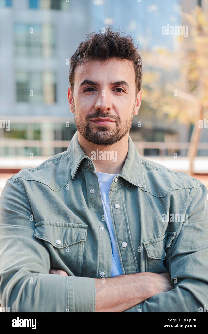 Selbstbewusste individuelle Pose mit überkreuzten Armen, die Charisma und Charme in einem professionellen Umfeld ausstrahlen und Selbstbewusstsein und Entschlossenheit in zeigen Stockfoto