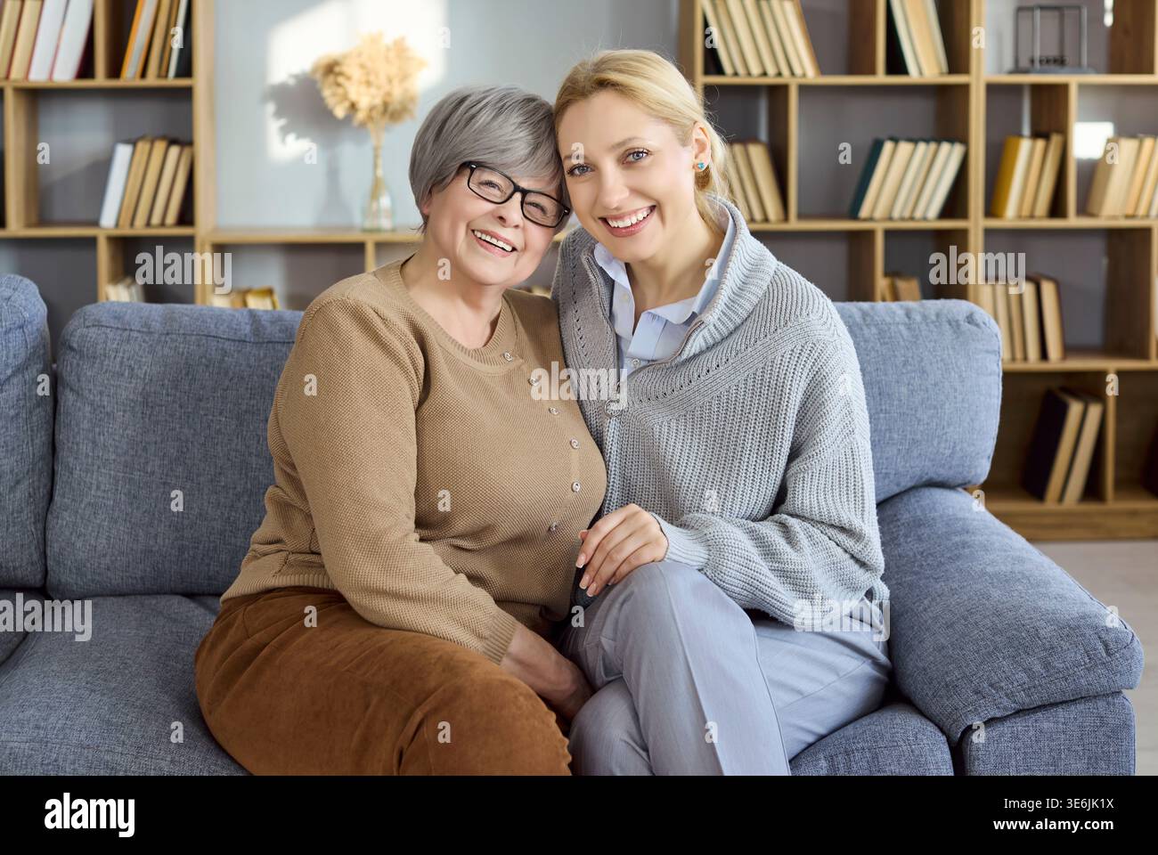 Glückliche Seniorenmutter und Erwachsene Tochter umarmen sich auf einem gemütlichen Heimsofa, Familienliebe Stockfoto