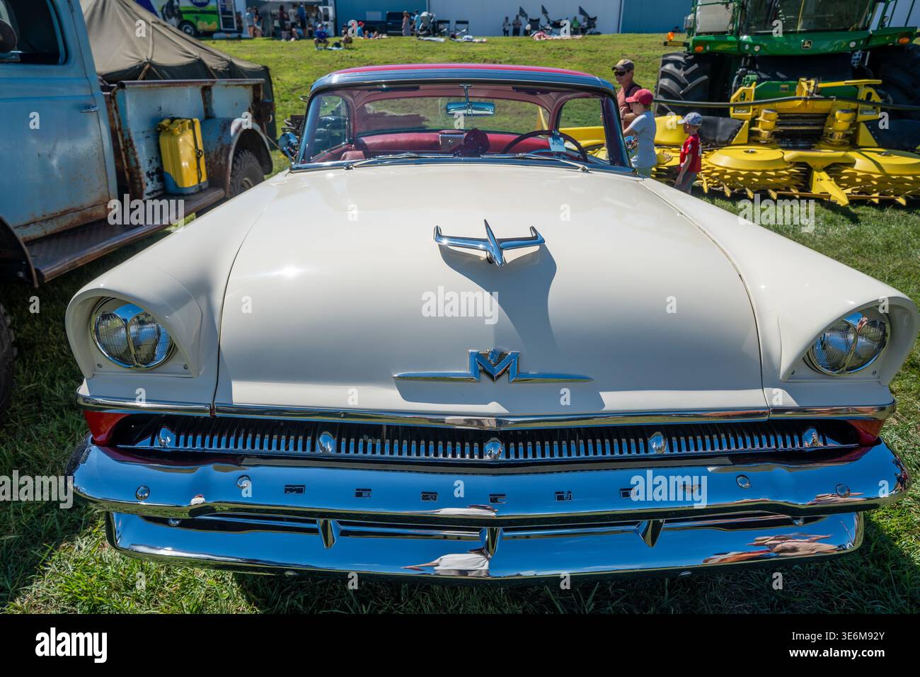 Oldtimer-Oldtimer in Creme, der auf einer Landwagenschau im Freien mit auffälligem verchromtem Kühlergrill, Kapuzenverzierung und zweifarbigem Design fotografiert wurde Stockfoto