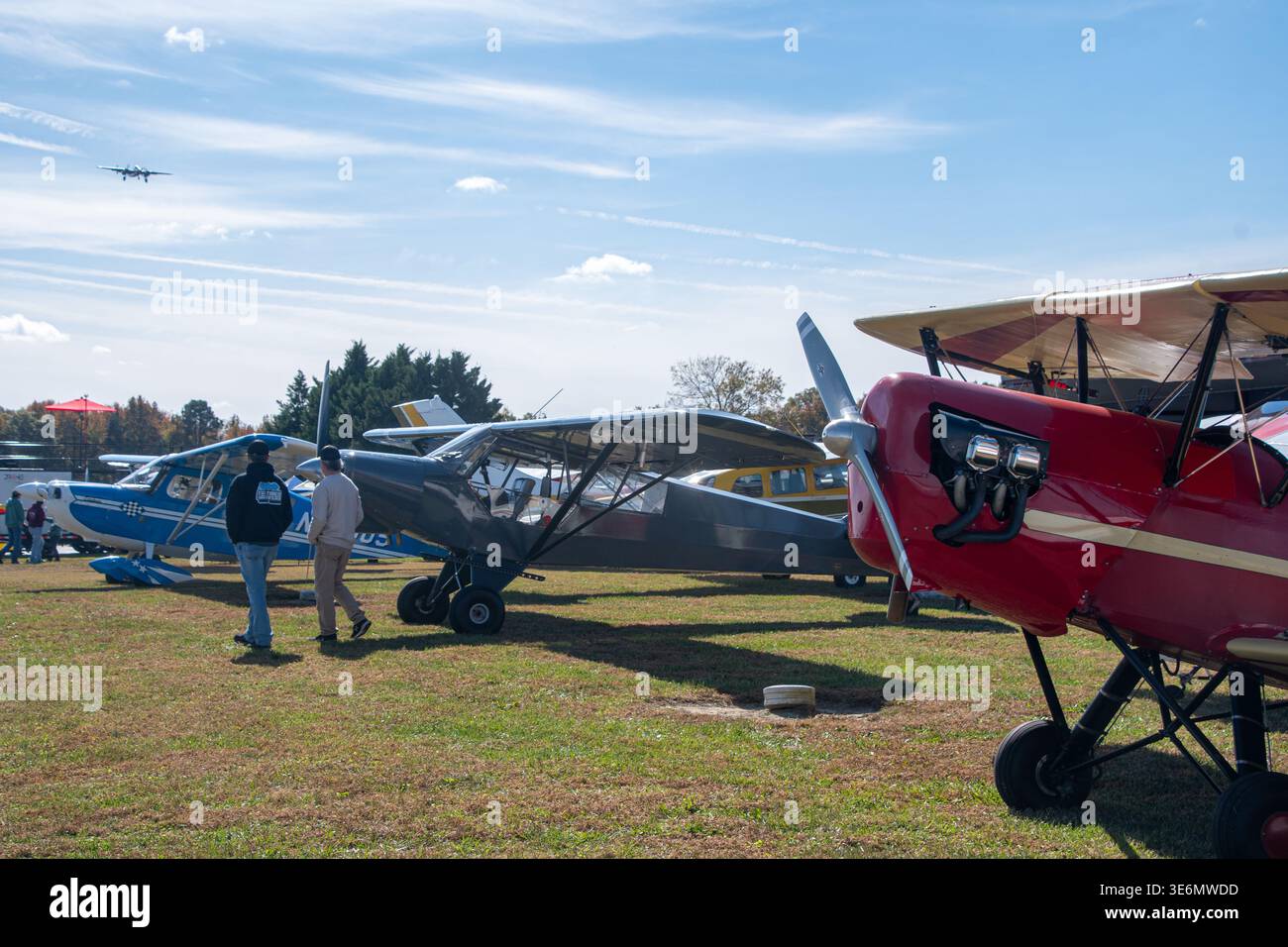 Besucher schlendern zwischen alten kleinen Flugzeugen, die auf Gras auf einer Outdoor-Flugshow in den USA geparkt werden, mit einem hellen Himmel, einem klassischen Doppeldecker im F Stockfoto
