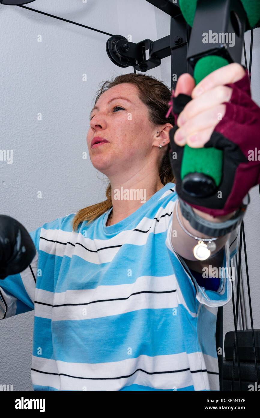 Frau, die Krafttraining im Fitnessstudio zu Hause mit fokussiertem Ausdruck durchführt Stockfoto