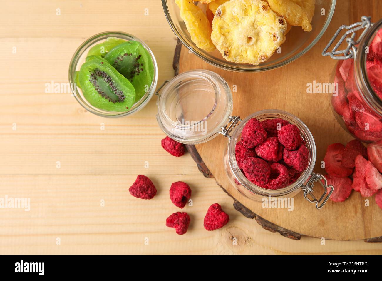 Schüsseln und Gläser mit verschiedenen getrockneten Früchten und Beeren auf hölzernem Hintergrund Stockfoto