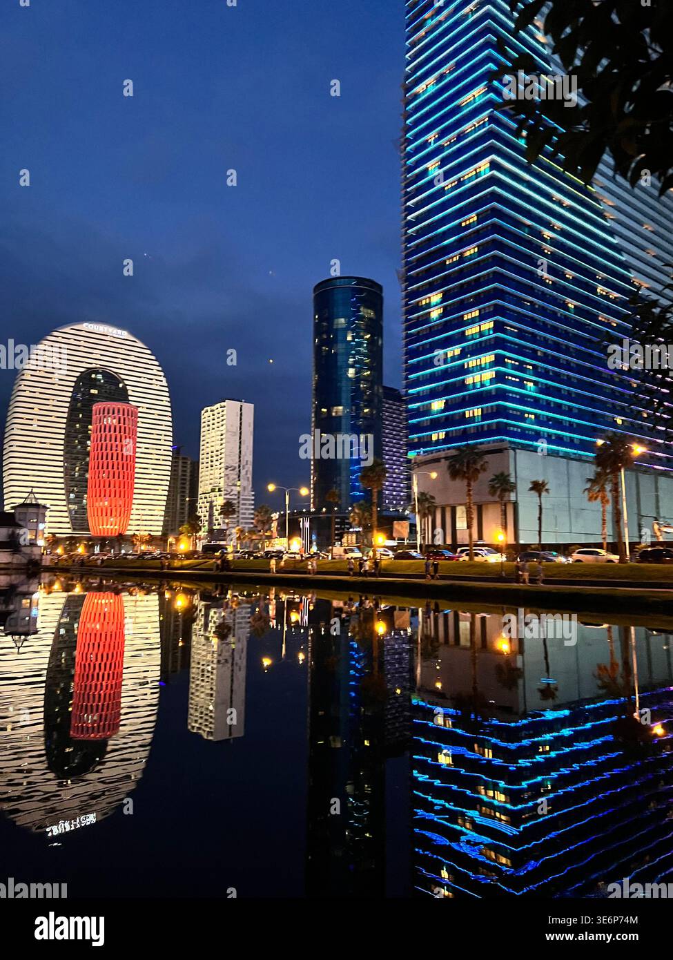 Nächtliche Reflexionen der modernen Türme am Wasser in Batumi, Georgia, einschließlich des Courtyard-Hotelgebäudes. - Smartphone-aufgenommenes Stockfoto
