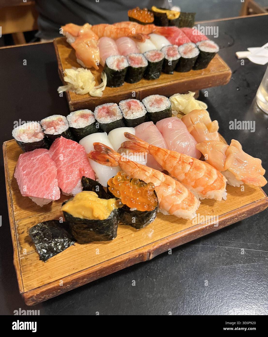 Verschiedene Sushi-, Nigiri- und Maki-Brötchen werden auf Holztabletts in einem Restaurant in Tokio, Japan, serviert. Stockfoto