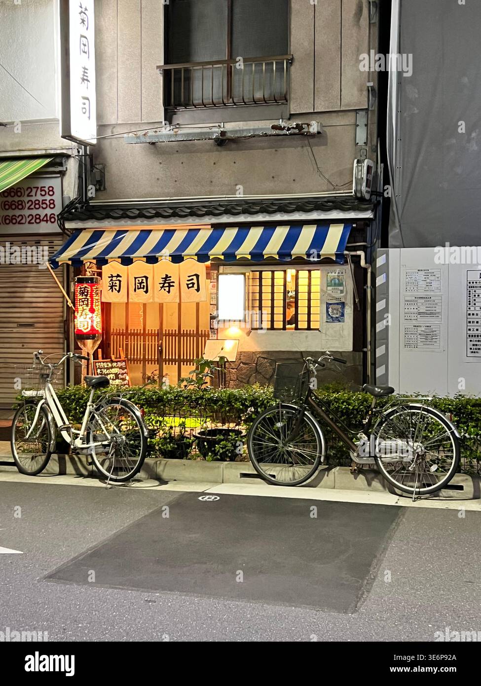 Kleines japanisches Restaurant mit geparkten Fahrrädern in einer ruhigen Straße in Tokio, Japan. - Smartphone-aufgenommenes Stockfoto