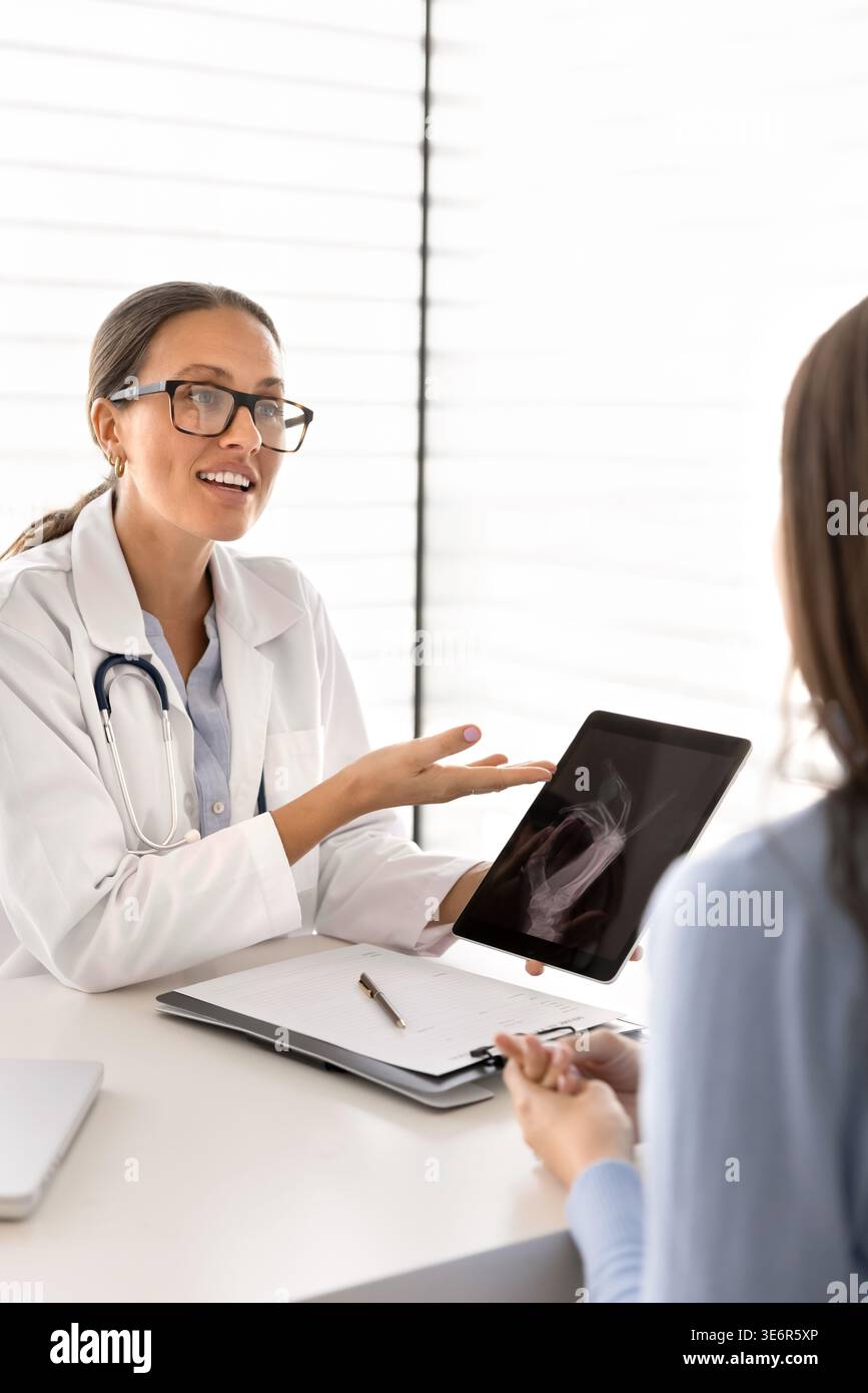 Ärztin mit digitalem Tablet, das dem Patienten einen medizinischen Scan zeigt Stockfoto