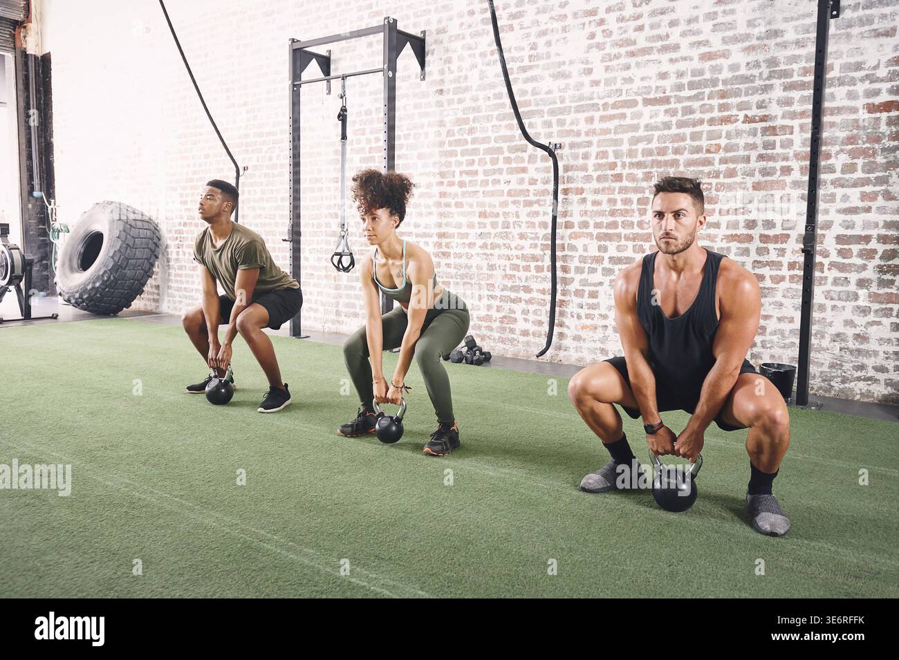 Kettlebells, Squat und Menschen im Fitnessstudio, Training für gesundheitliche Vorteile und Herausforderung. Morgenroutine, Männer und Frauen in der Einrichtung, Ausrüstung für Workout oder Stockfoto