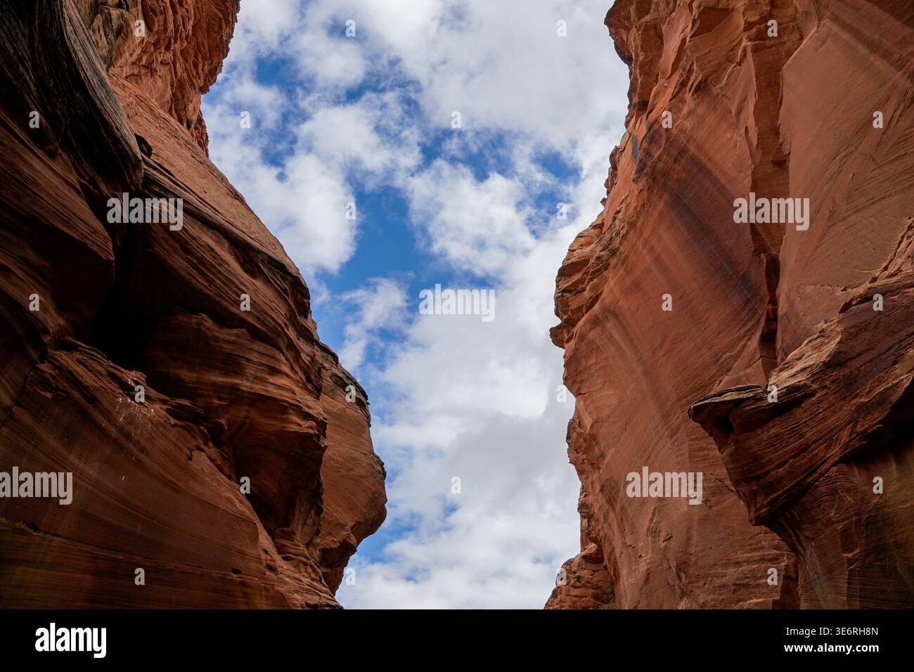 Hoch aufragende Sandsteinmauern ragen auf beiden Seiten unter einem teilweise bewölkten Himmel auf und zeigen vertikale Felsformationen und natürliche Erosion. Stockfoto