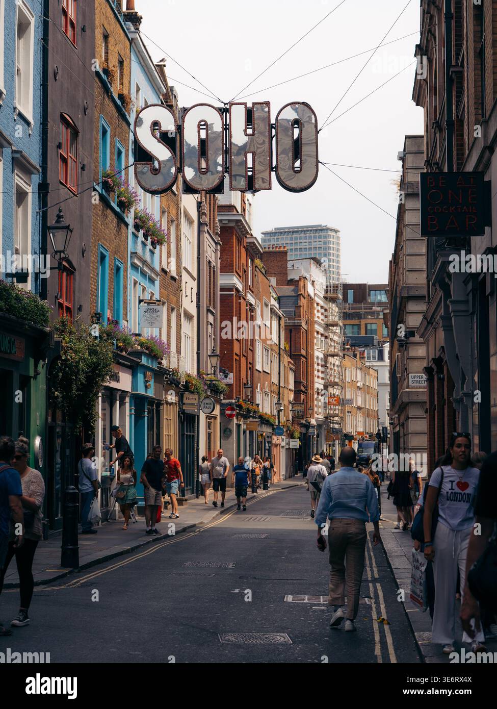 London, Großbritannien - 20. Juni 2025: Blick auf die lebhafte Soho Street, wimmelt von Fußgängern inmitten farbenfroher Gebäude und dem berühmten „SOHO“-Schild Stockfoto