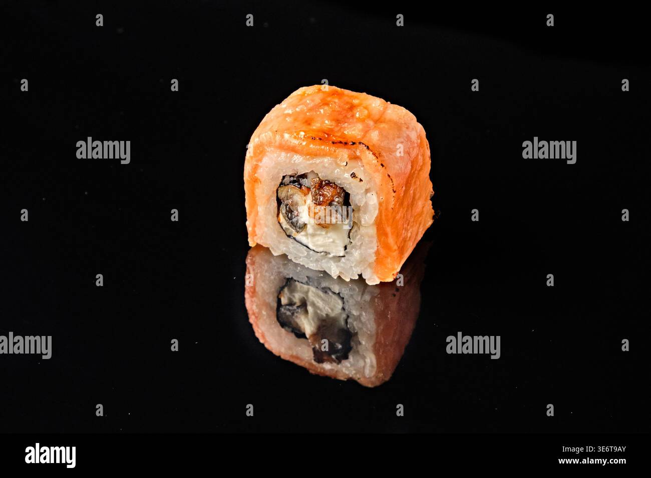 Zwei Sushi-Brötchen mit Lachs, eines mit gegrilltem Aal und Frischkäse gefüllt, eines mit goldener knuspriger Spitze und Meersalz gebacken, Stockfoto