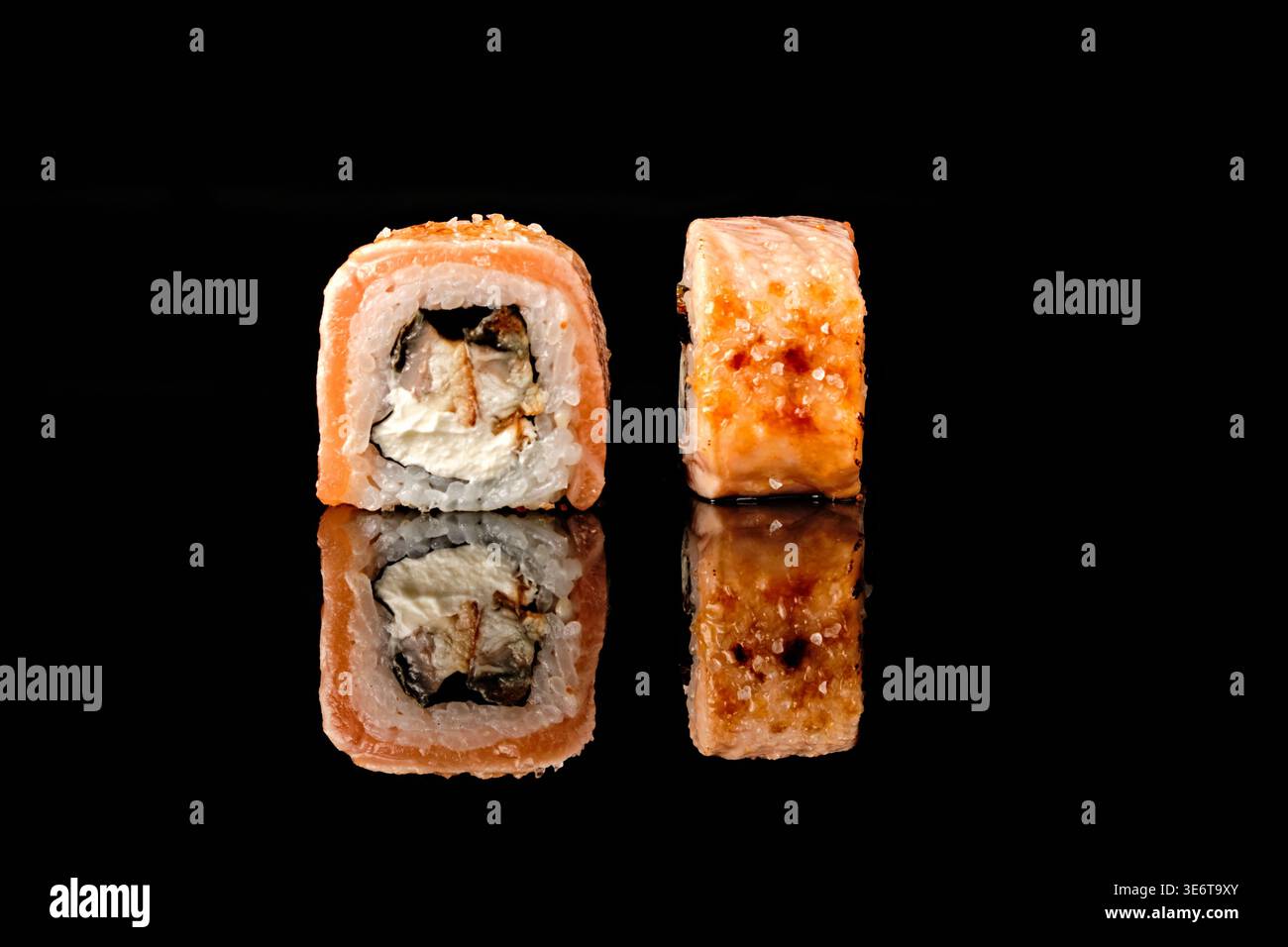 Zwei Sushi-Brötchen mit Lachs, eines mit gegrilltem Aal und Frischkäse gefüllt, eines mit goldener knuspriger Spitze und Meersalz gebacken, Stockfoto