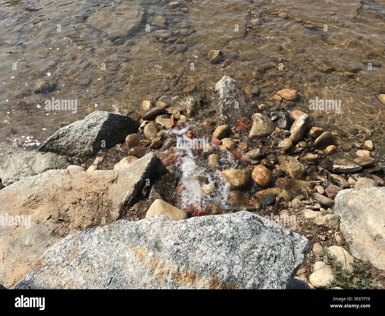 Felsiges Lakeshore mit kleiner Wasserkaskade, die über Stones fließt Stockfoto