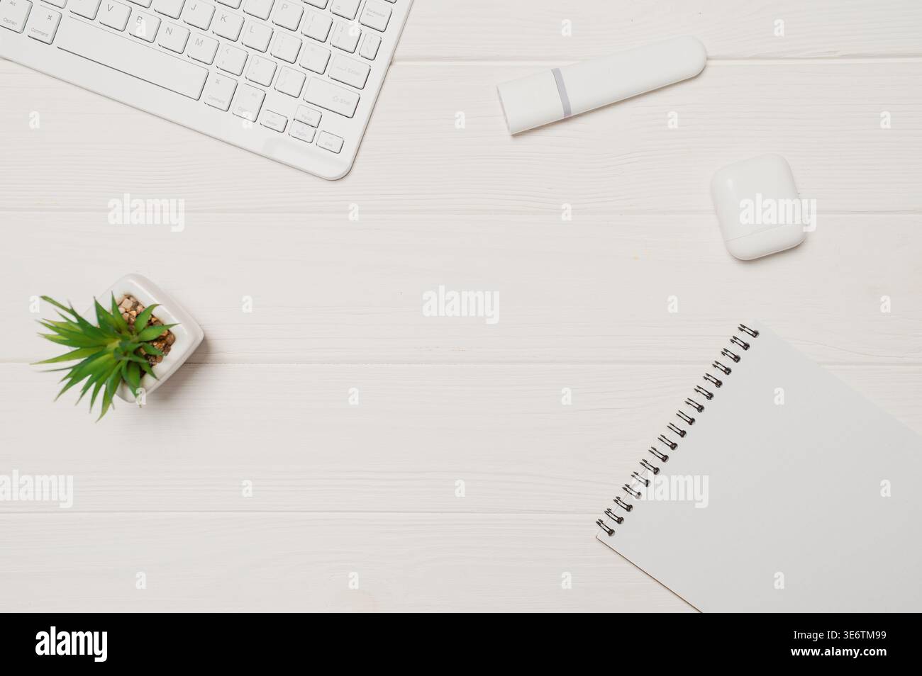 Minimaler Büroschreibtisch für Remote-Arbeiten mit weißer Tastatur, Anlage, Marker, Notebook und Ohrstöpsel auf Holz Stockfoto