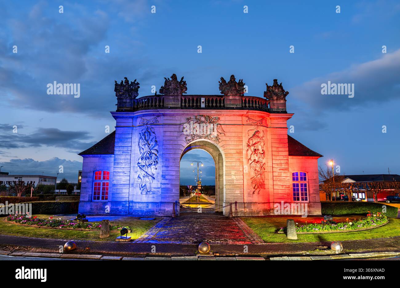 Das historische Steintor Porte du Pont, beleuchtet mit den Farben der französischen Flagge in der Abenddämmerung in Vitry-le-Francois, Frankreich. Stockfoto