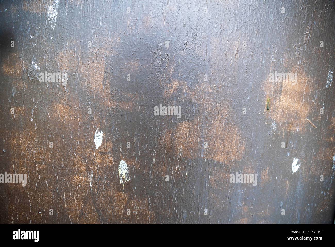 Dunkle Metalloberfläche mit sichtbaren Pinselstrichen und braunen Rostflecken. Stockfoto