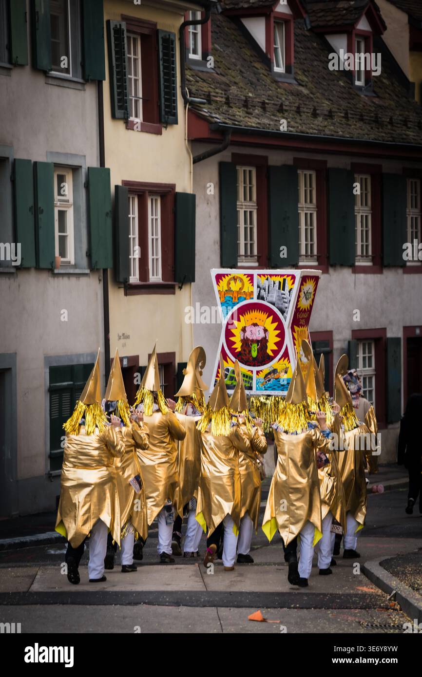 Basel, Schweiz - 10. März 2025: Blick auf goldverkleidete Figuren ziehen durch die historische Fasnacht, ihre spitzen Hüte und Kostüme schimmern wieder Stockfoto