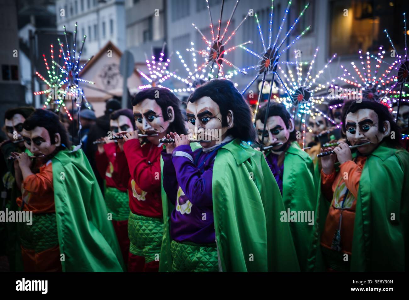 Basel, Schweiz - 10. März 2025: Der Blick auf maskierte Darsteller in lebhaften Kostümen zieht die Fasnacht hinunter, deren Flöten durch die historische Straße hallten Stockfoto