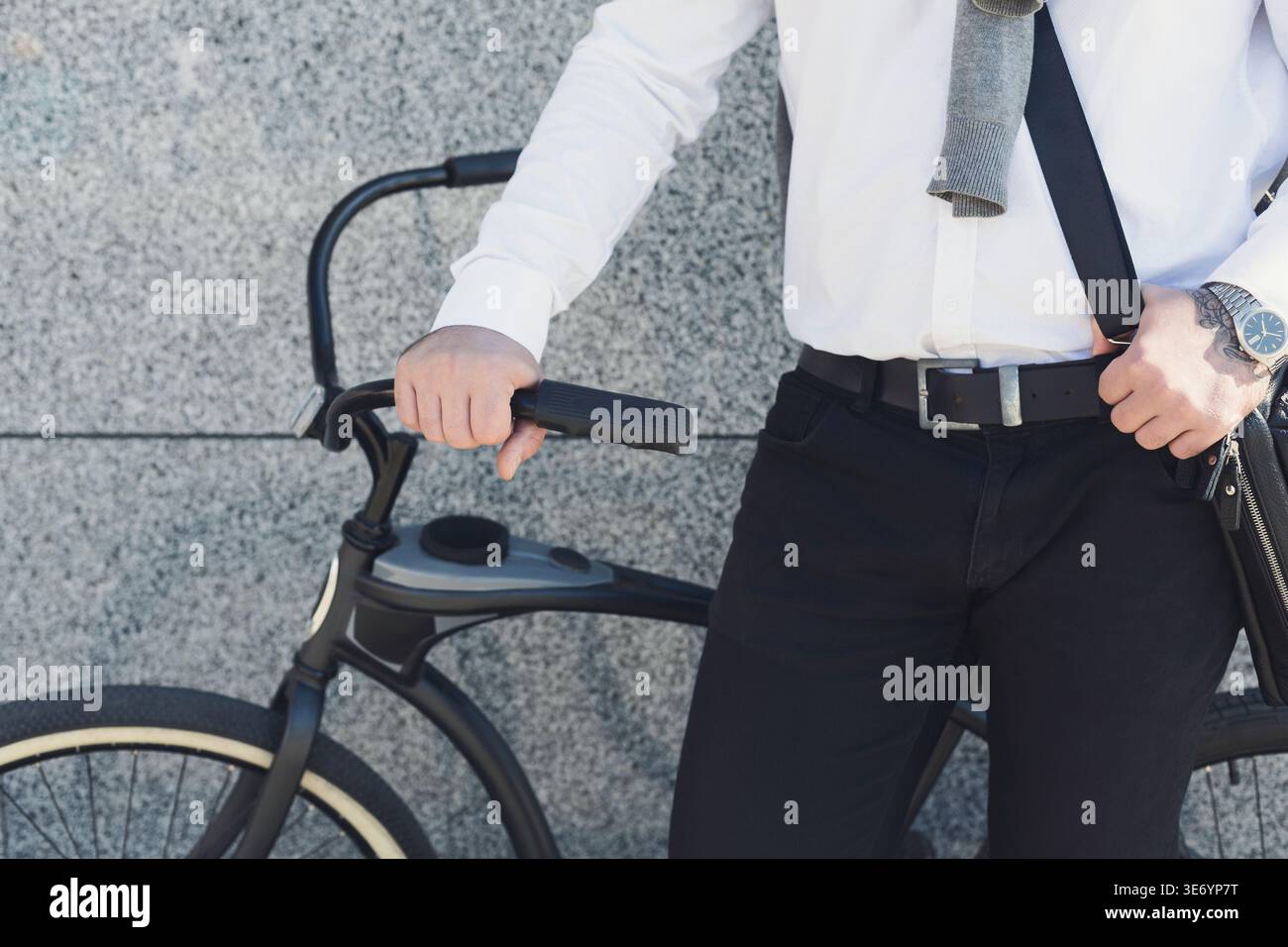 Geschäftsmann hält Hand an seinem Fahrrad, während er draußen steht Stockfoto