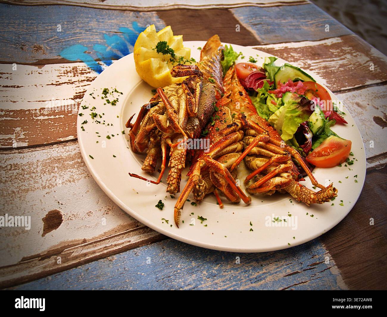 Gegrillter Hummer mit frischem Salat und Zitrone auf rustikalem Tisch Stockfoto