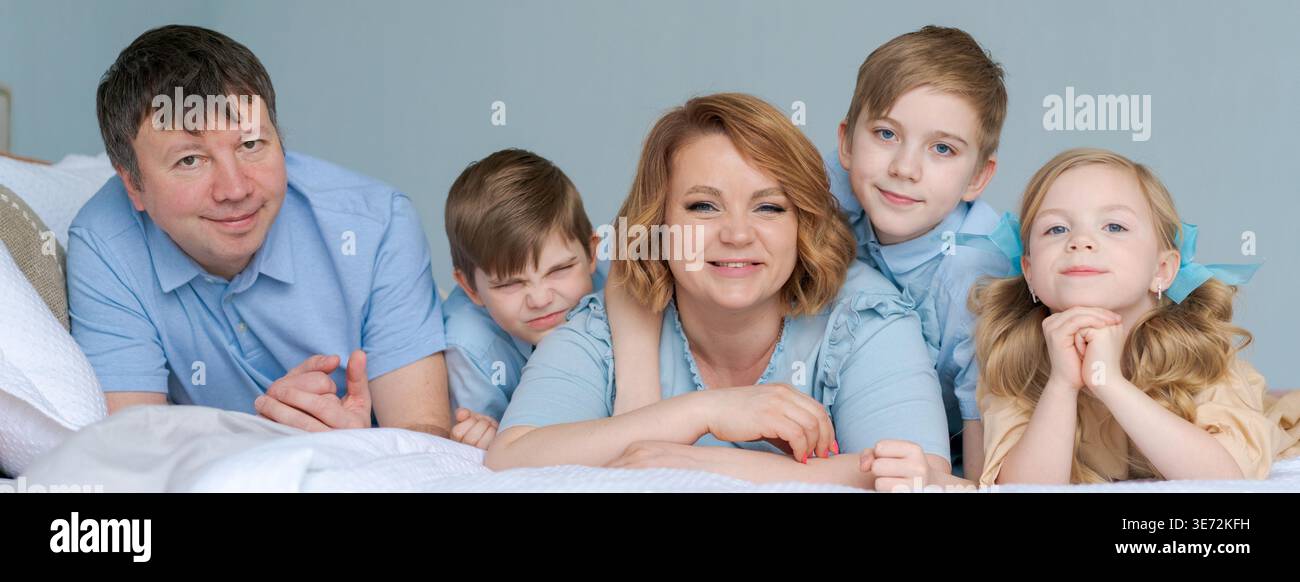 Fröhliche Familie spielt zusammen auf dem Bett. Die Eltern verbringen ihre Freizeit mit ihrer Tochter und zwei Söhnen. Große kaukasische Familie spielt zu Hause im Schlafzimmer. Mama und Papa machen sich mit den Kindern durch die Gegend Stockfoto