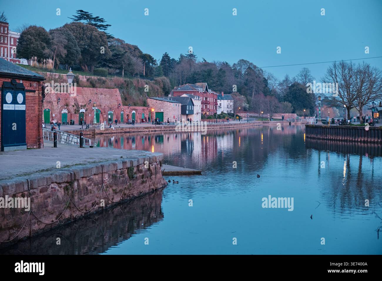 Exeter, Vereinigtes Königreich - 20. März 2026. Historische Sandsteinlager im Exeter Canal Basin schimmern in der Abenddämmerung im Fluss exe Stockfoto