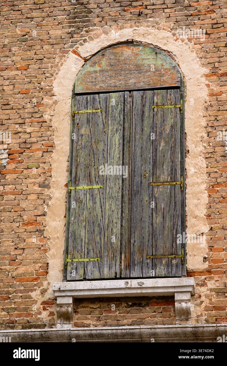 Ein altes, geschlossenes Fenster oder eine Tür mit Holzläden in einem Backsteingebäude im Zentrum von Split, Kroatien. Stockfoto