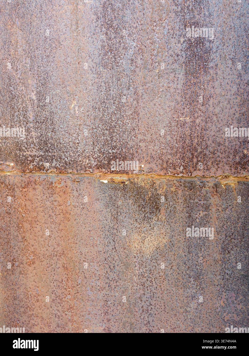 Eine detaillierte Makroaufnahme einer stark oxidierten Metalloberfläche mit einer horizontalen Schweißnaht und einem schönen Farbverlauf von Rostfarben von Orange Stockfoto