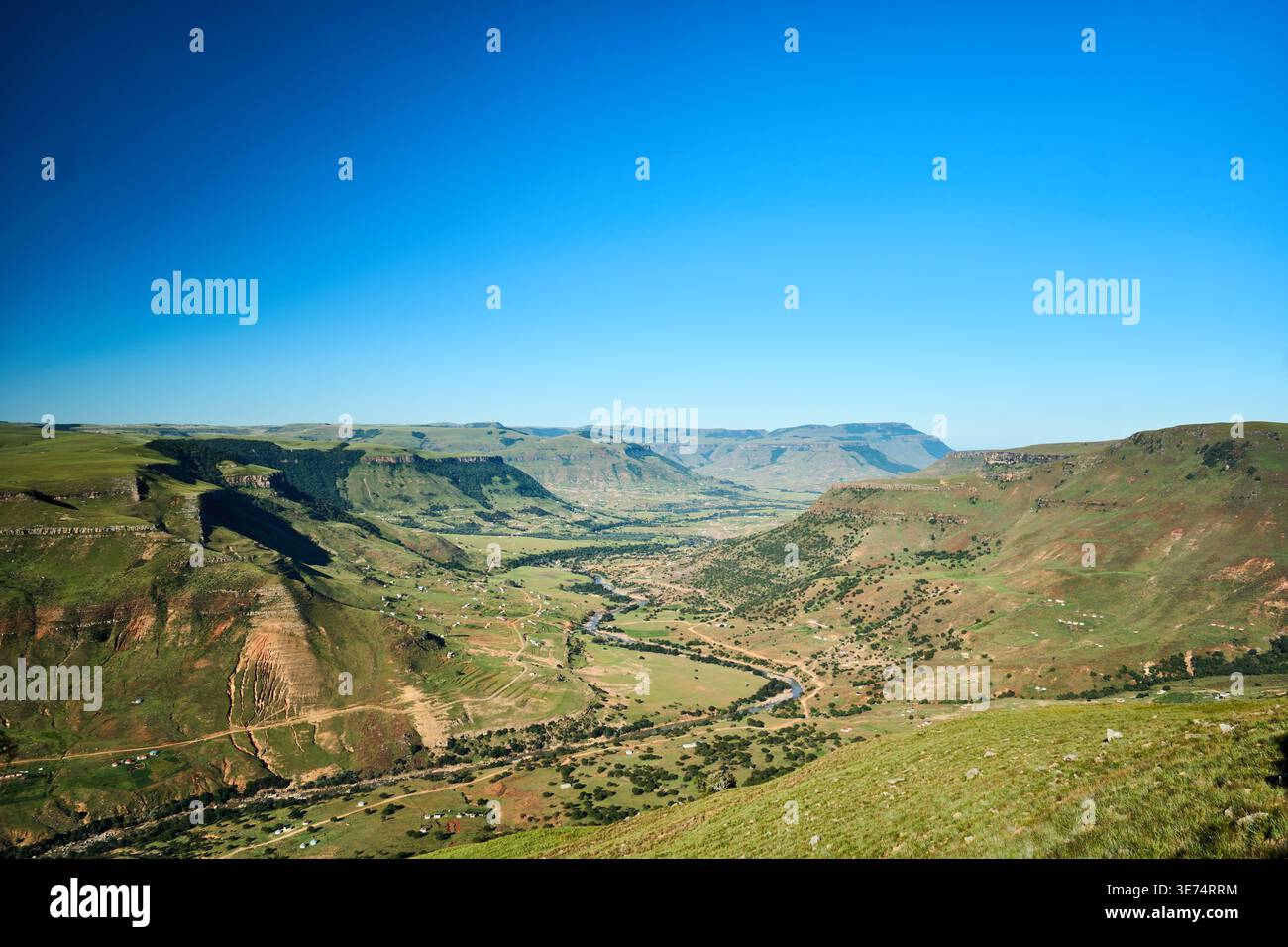 Riesiges, grünes Tal unter klarem azurblauen Himmel mit weit entfernten Bergrücken Stockfoto