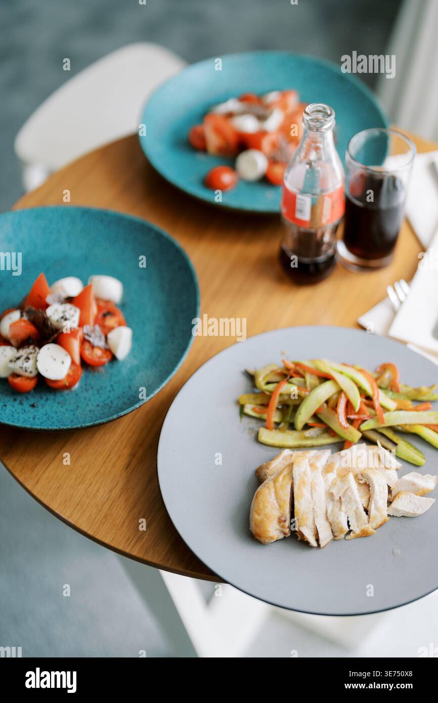 Köstliche Essenspräsentation. Schön angerichtetes gegrilltes Huhn, begleitet von frischem Gemüse Stockfoto