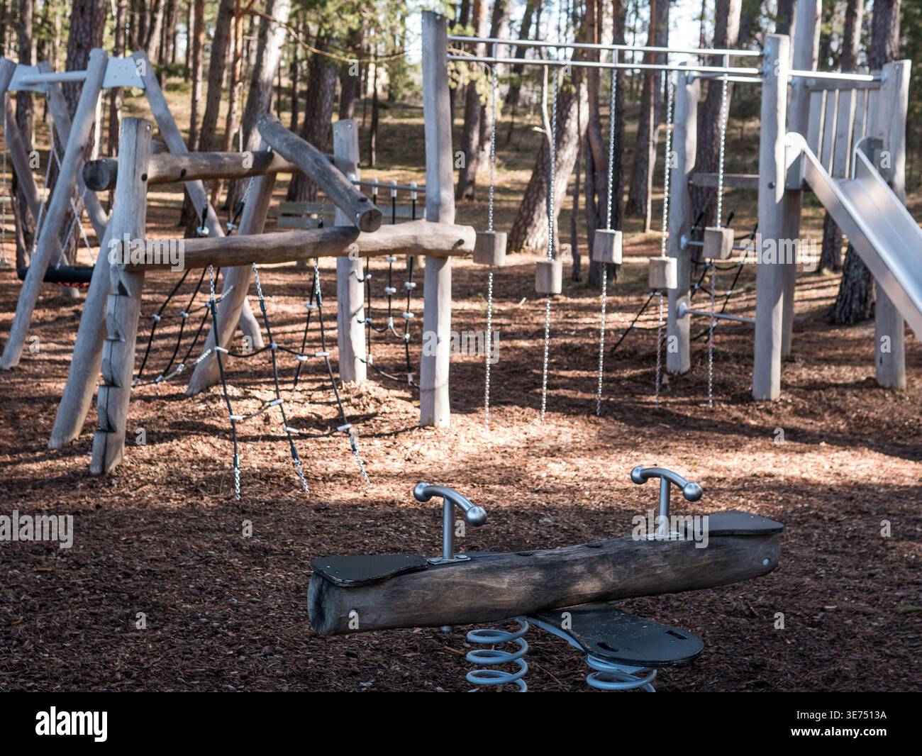 Leerer hölzerner Spielplatz im Pine Forest - natürlicher Kinderspielplatz im Frühjahr Stockfoto